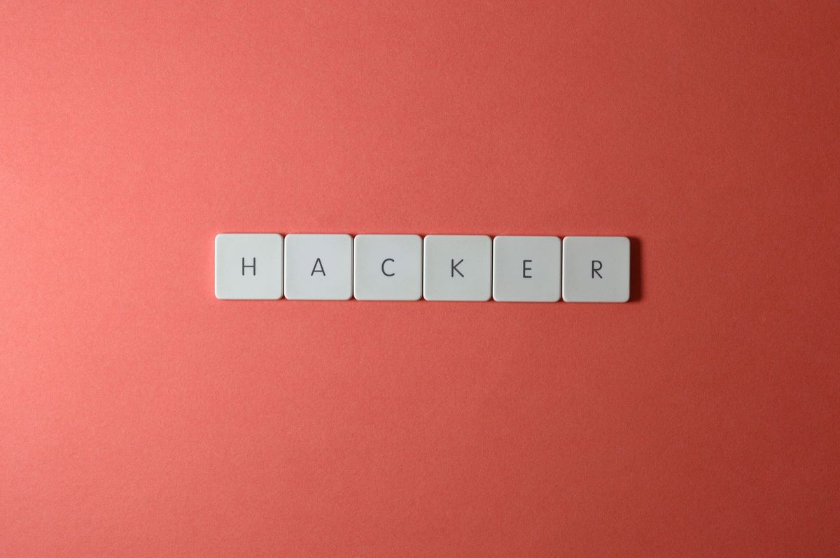 Close-up of the word 'HACKER' made with letter tiles on a red background, emphasizing cybersecurity.
