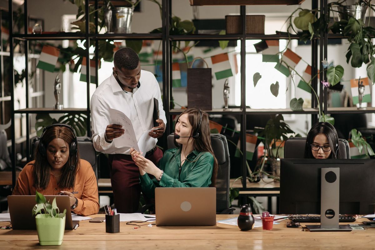 A diverse group of colleagues collaborating in a modern office environment with plants and technology.