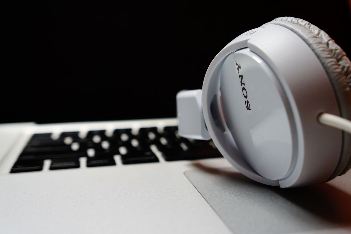 White headphones resting on a laptop keyboard, highlighting modern technology.