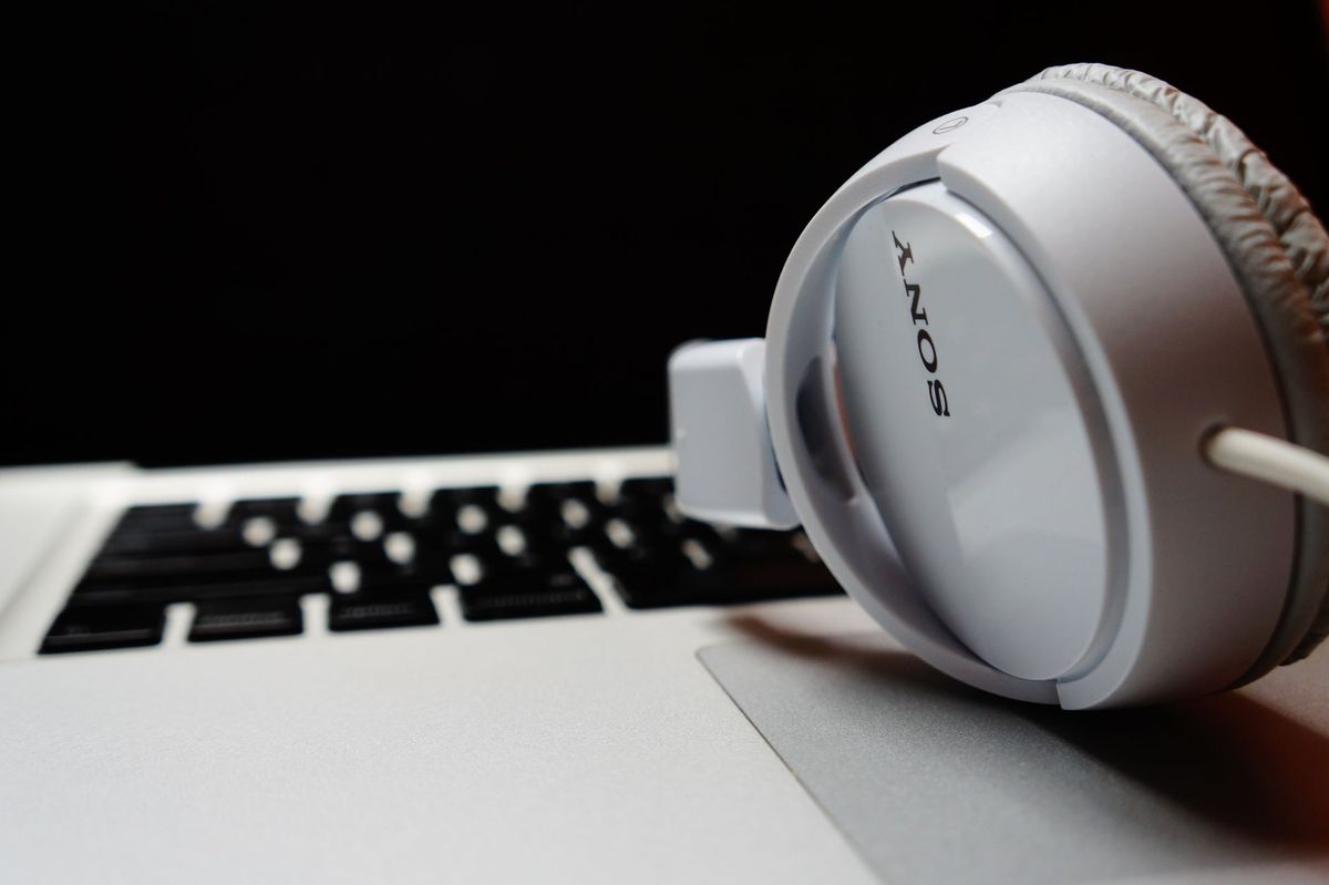 White headphones resting on a laptop keyboard, highlighting modern technology.