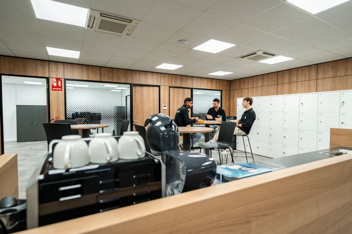 Three people are chatting in a modern office space.