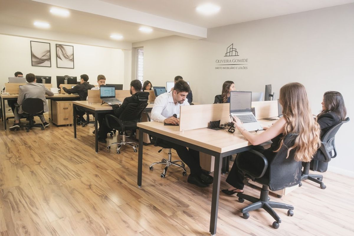 Modern open-plan office with employees working at individual workstations.