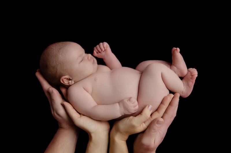 Novorozenec v rukou rodičů na černém pozadí, fotoateliér Praha.