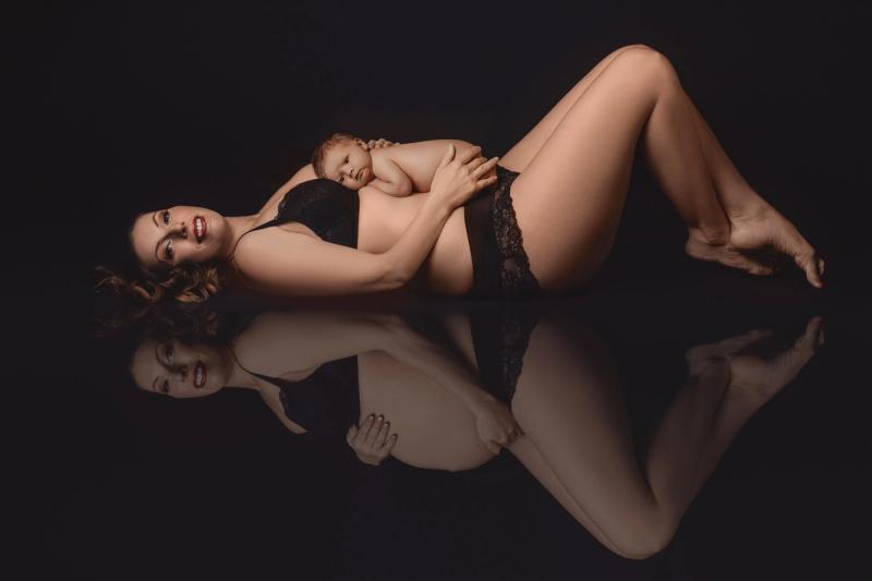 Maminka s novorozencem na černém pozadí, odraz v zrcadle.