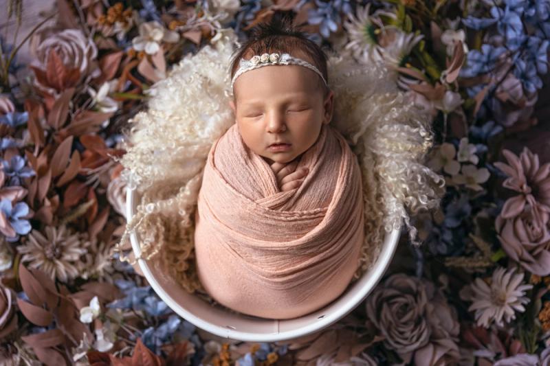 Miminko holčička v bílém kyblíku s lososovým wrapem a čelenkou.