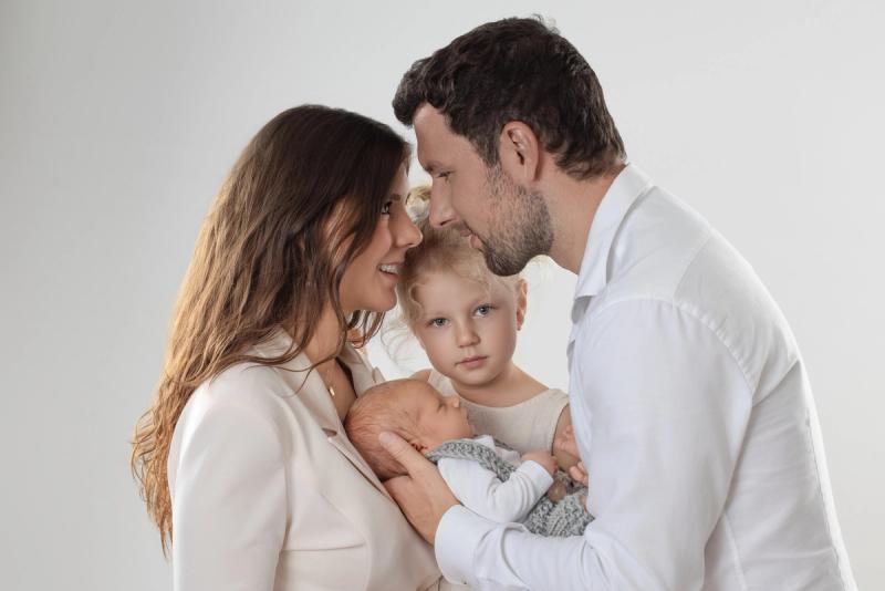 Rodinná fotografie rodičů se starším dítětem na světlém pozadí.