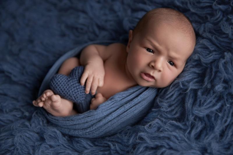 Miminko v tmavě modrém wrapu na modré kožešině, portrét ze studia.