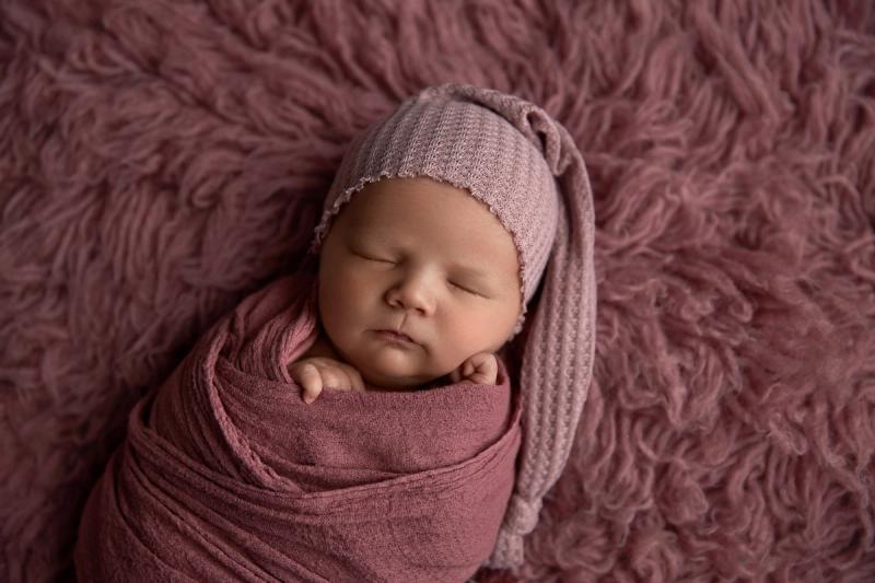 Miminko holčička ve starorůžovém wrapu se špičatou čepičkou.