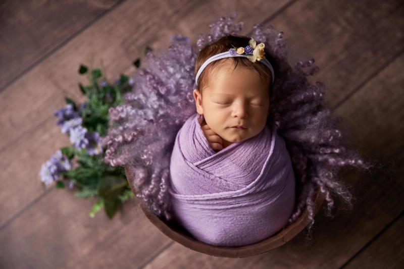 Miminko holčička v dřevěném košíčku s fialovým wrapem a levandulí.