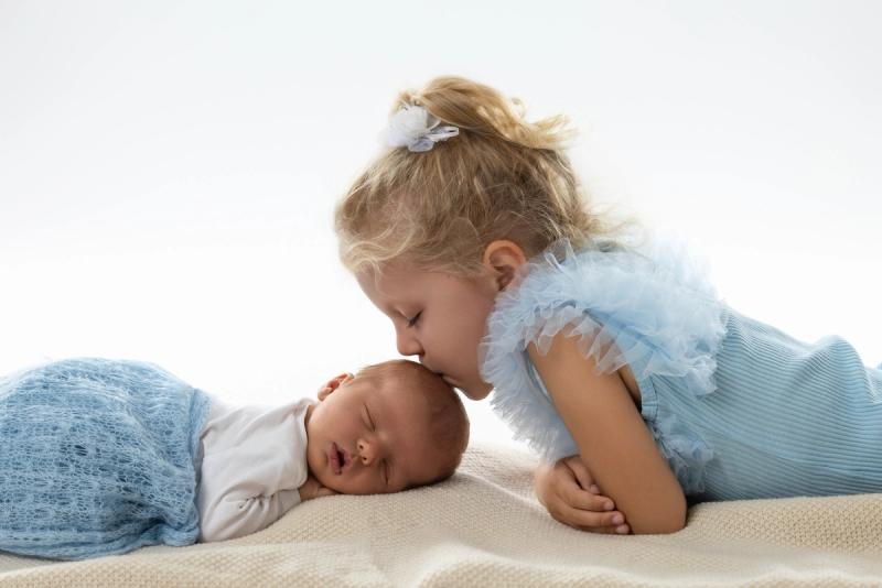 Sourozenecké foto na zemi s pusou v modrých šatech.