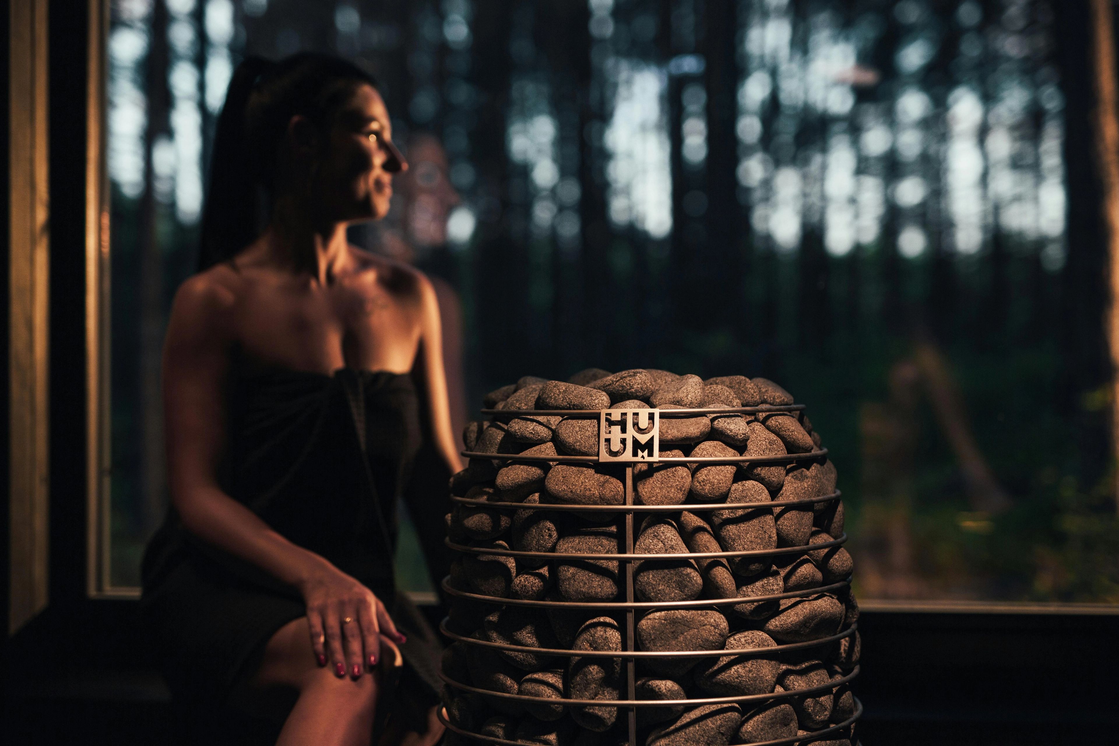 En dame i badstue, med utsikt over skogen.