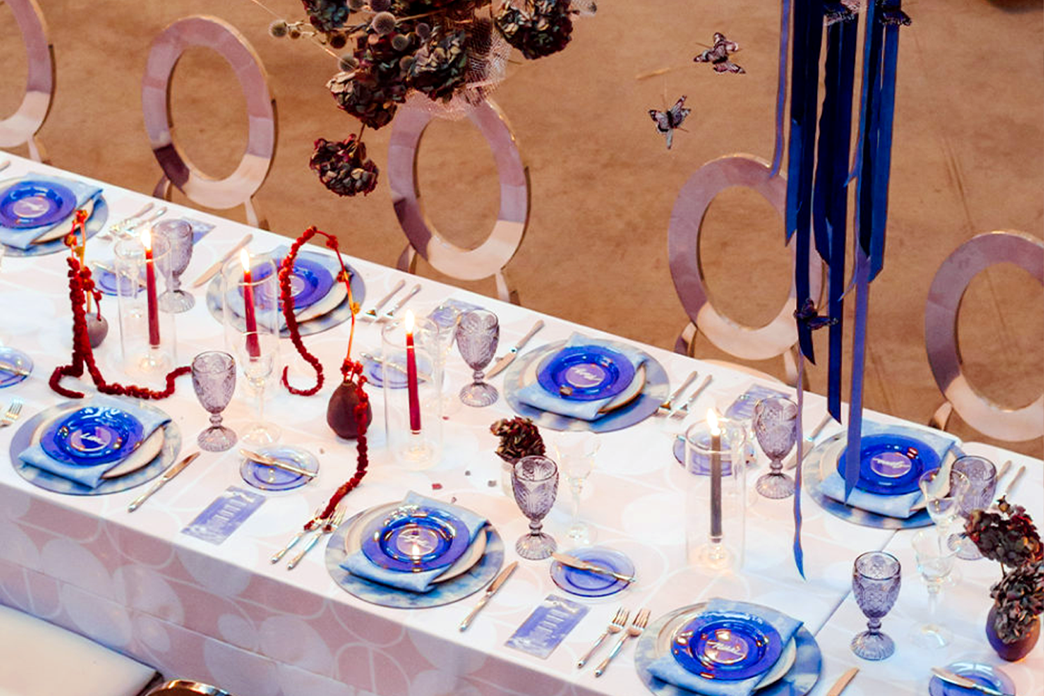 Rectangular table setting with blue glassware and floral arrangements