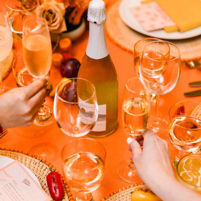 Orange monochromatic tablescape dinner party with champagne glass cheers