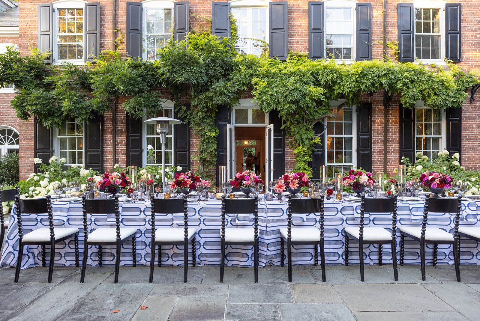 Blue patterned table linens at an outdoor dinner with floral centerpieces.