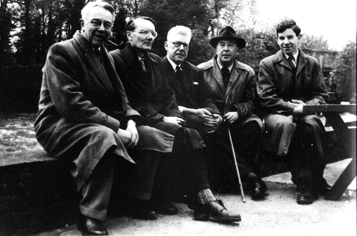 Five men sitting on a low wall outside. They are wearing wool coats.