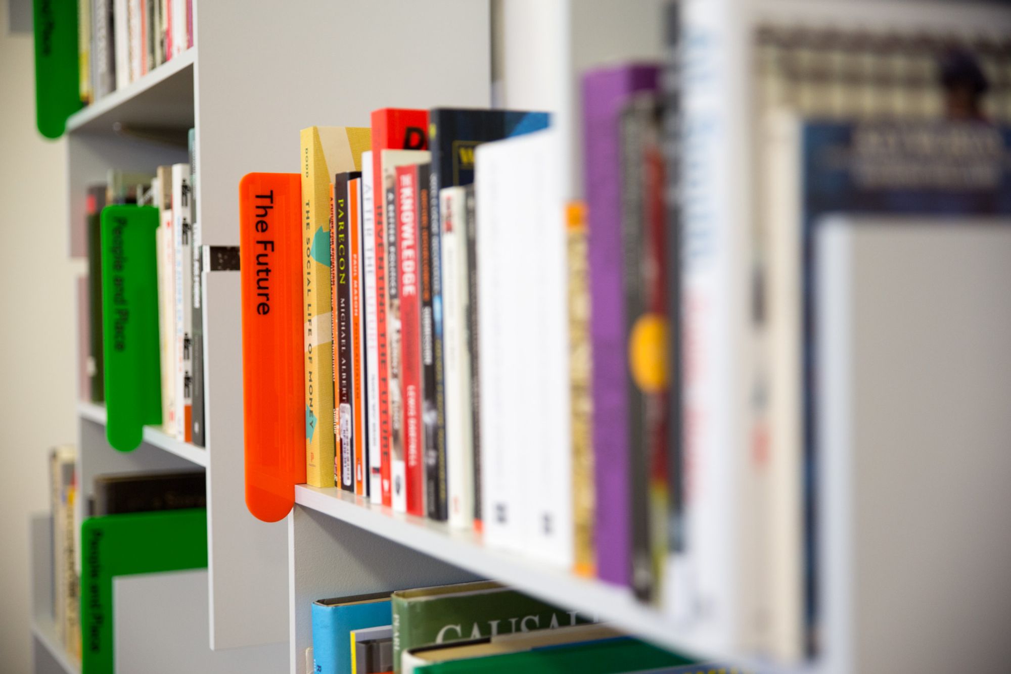 Wall mounted bookshelves full of books, viewed side-on, and several book dividers in view. The nearer one is orange and says The Future.