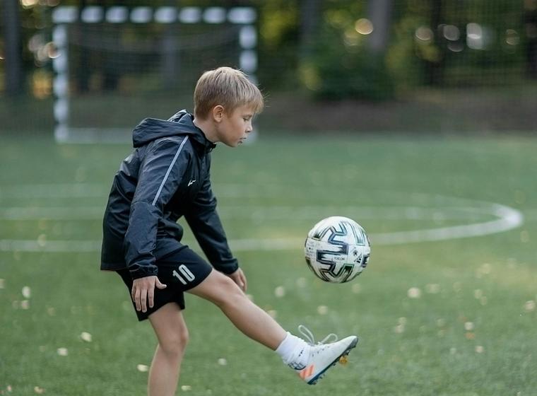 Young soccer player running on a field after recovering from a leg injury with physiotherapy