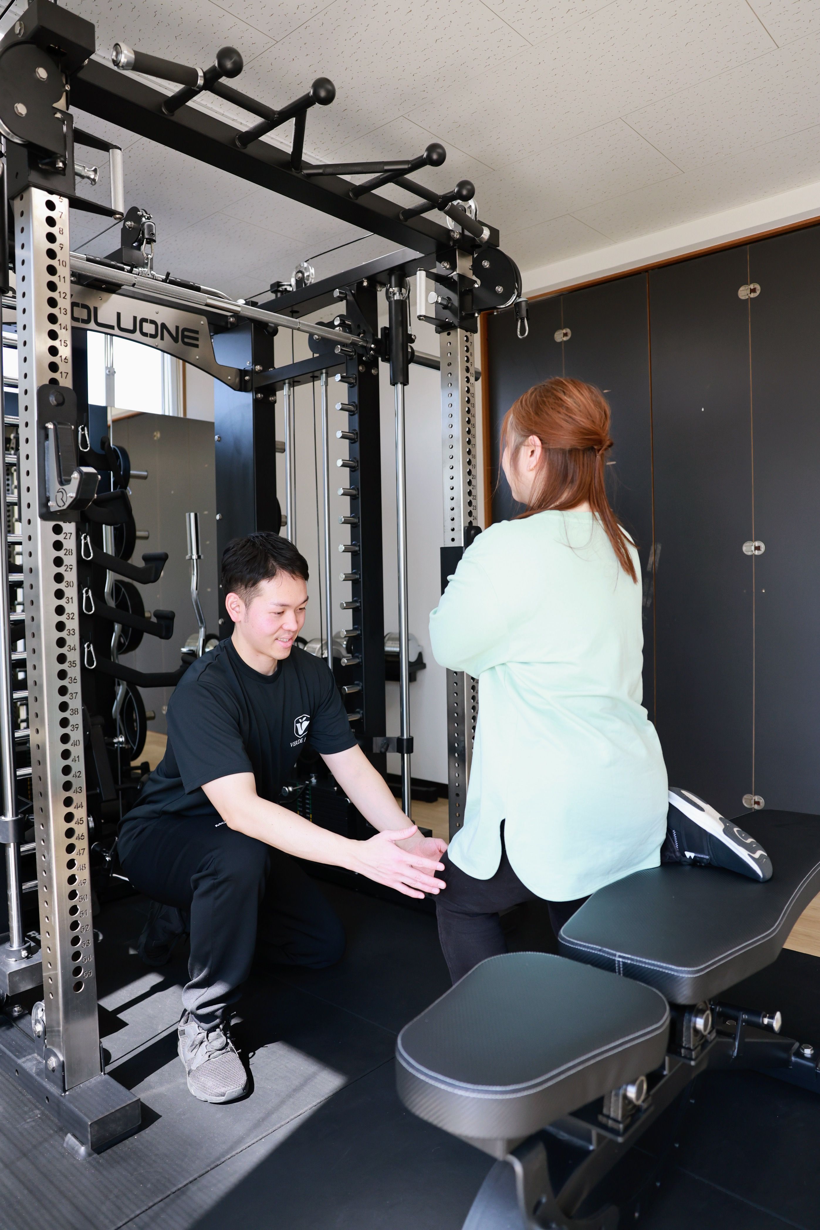 横手市のパーソナルジムVERDE FITでトレーナーがダンベルトレーニングをサポートする様子