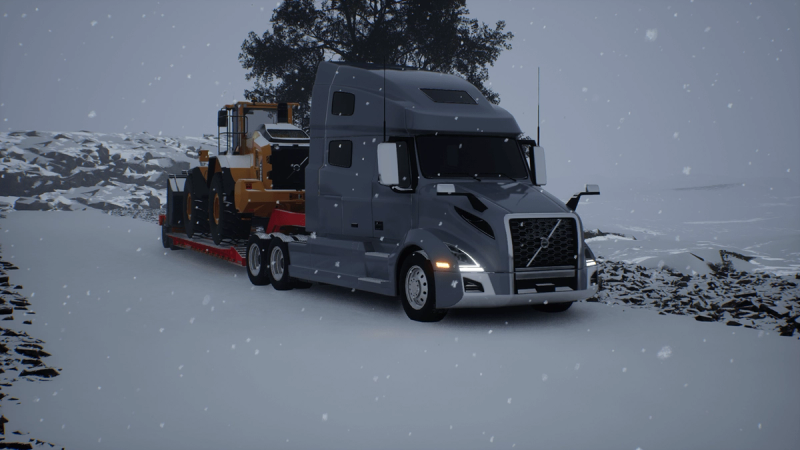 The same VNL and lowbed combination on a snow-covered road during active snowfall.