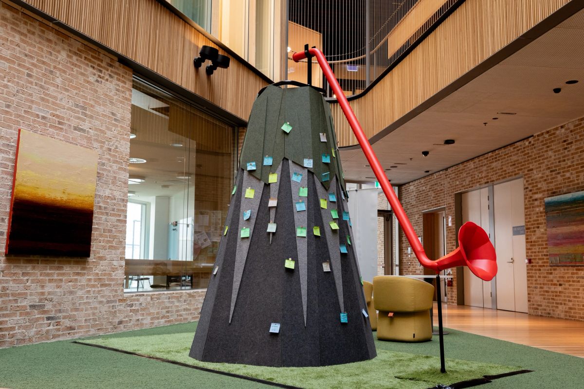 Inside the UTAS Inveresk Building, in Launceston, Is an grey, darker grey and green mountain, this is an interpretation of a mountain, this mountain also has long red horn stretching from the top to the bottom. On this mountain there are also stick notes pinned which speak power statements.