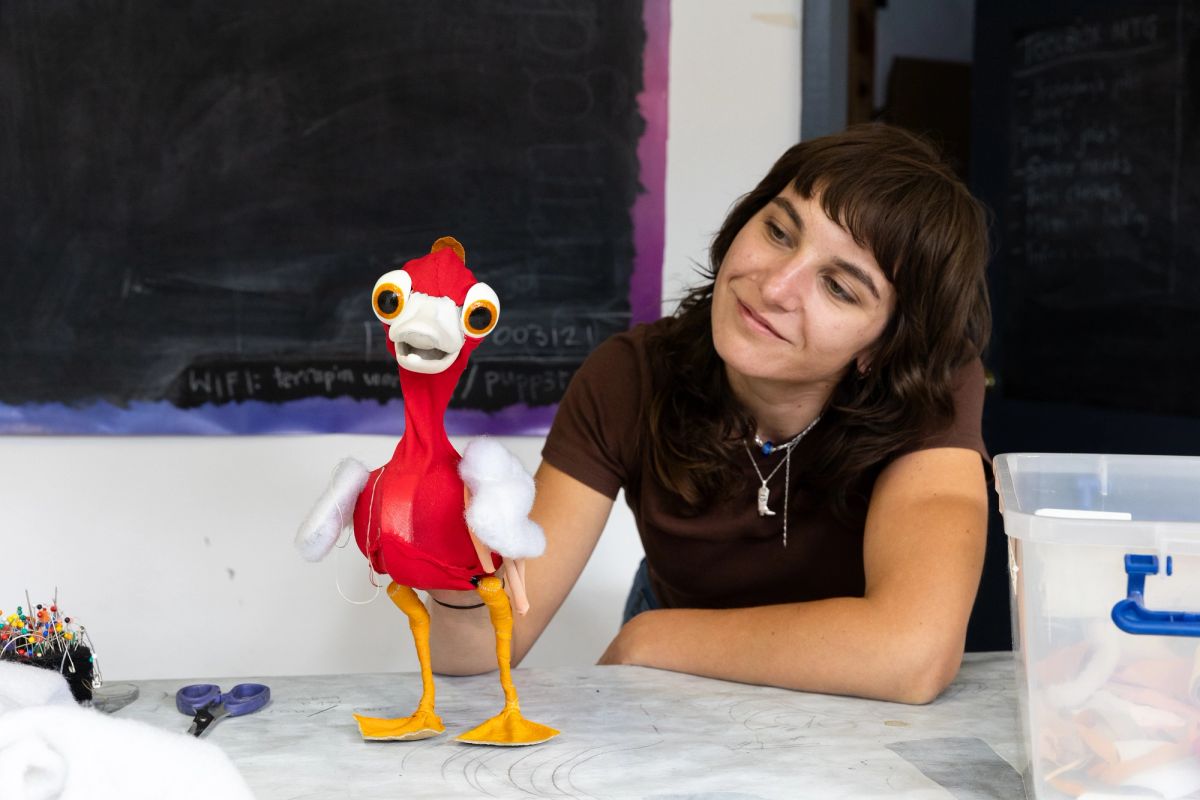 A person holds a red and yellow duck on a table