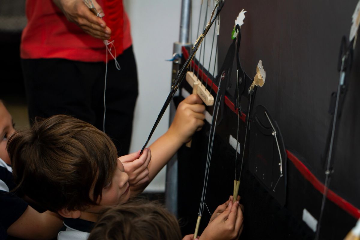 a group of children hold up shadow puppets to a screen