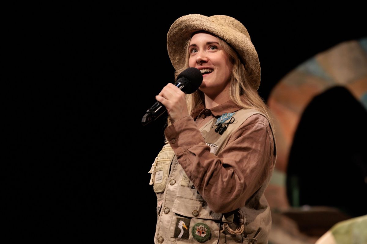 Performer Jem Nicholas, narrator of Feathers, wears a bird-watcher costume and speaks into a microphone on stage at Theatre Royal Hobart.