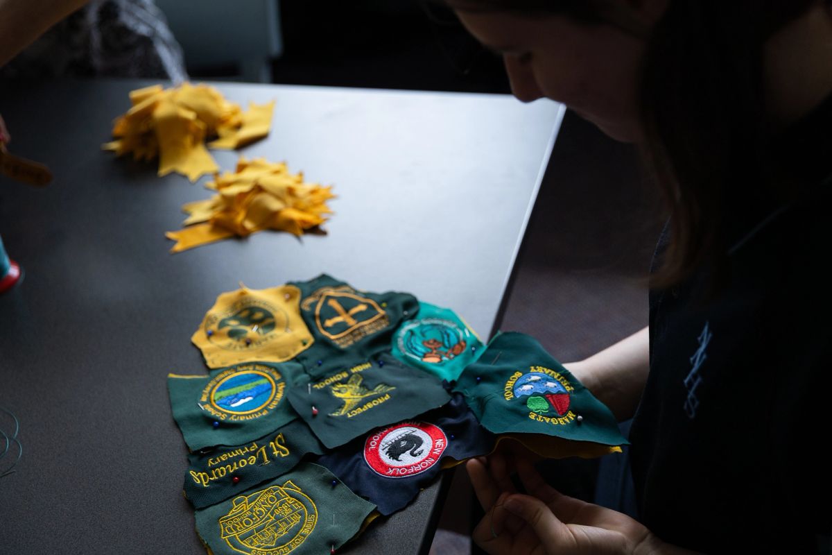 This is a map of school logos, these logos are all of the schools who have donated uniforms to the fur of Rum'un the TFC Devil Mascot. An unfinished Rum'un is hanging in the background, this was a making residency for artist Bryony Anderson to make the mascot with students from New Norfolk High School