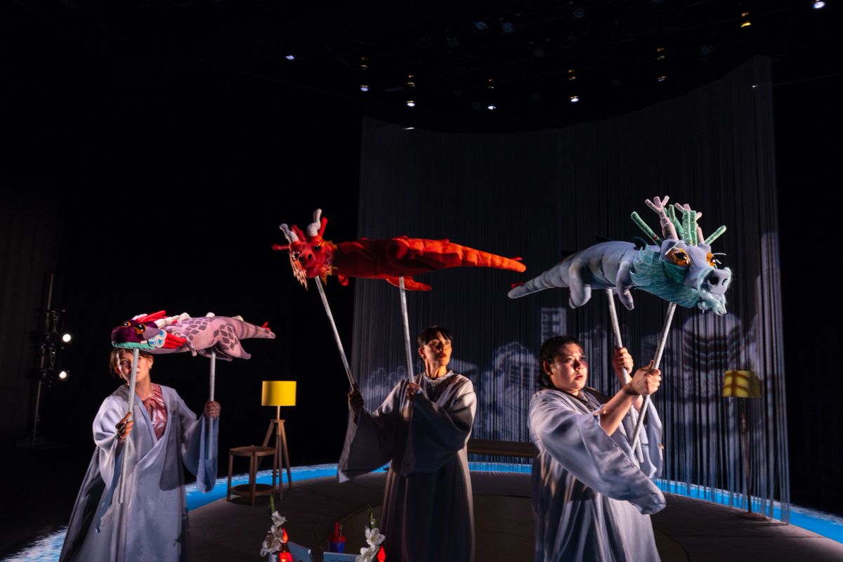 Three performers dressed in soft, flowing robes hold up three dragon puppets. The trio represent a grandmother, mother, and daughter in The Story of Chi, performed at Adelaide Festival Centre as part of OzAsia Festival 2024.