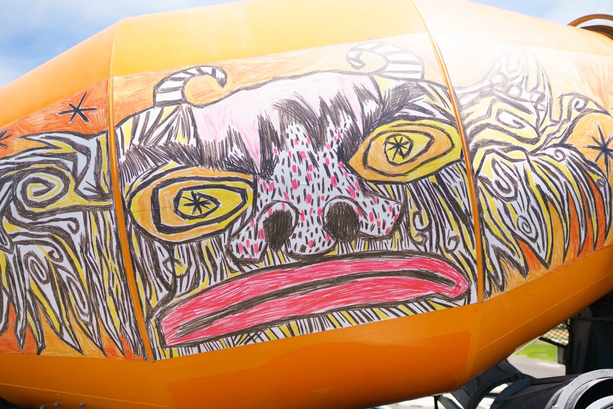 A graphic designed face is on an orange cement mixer