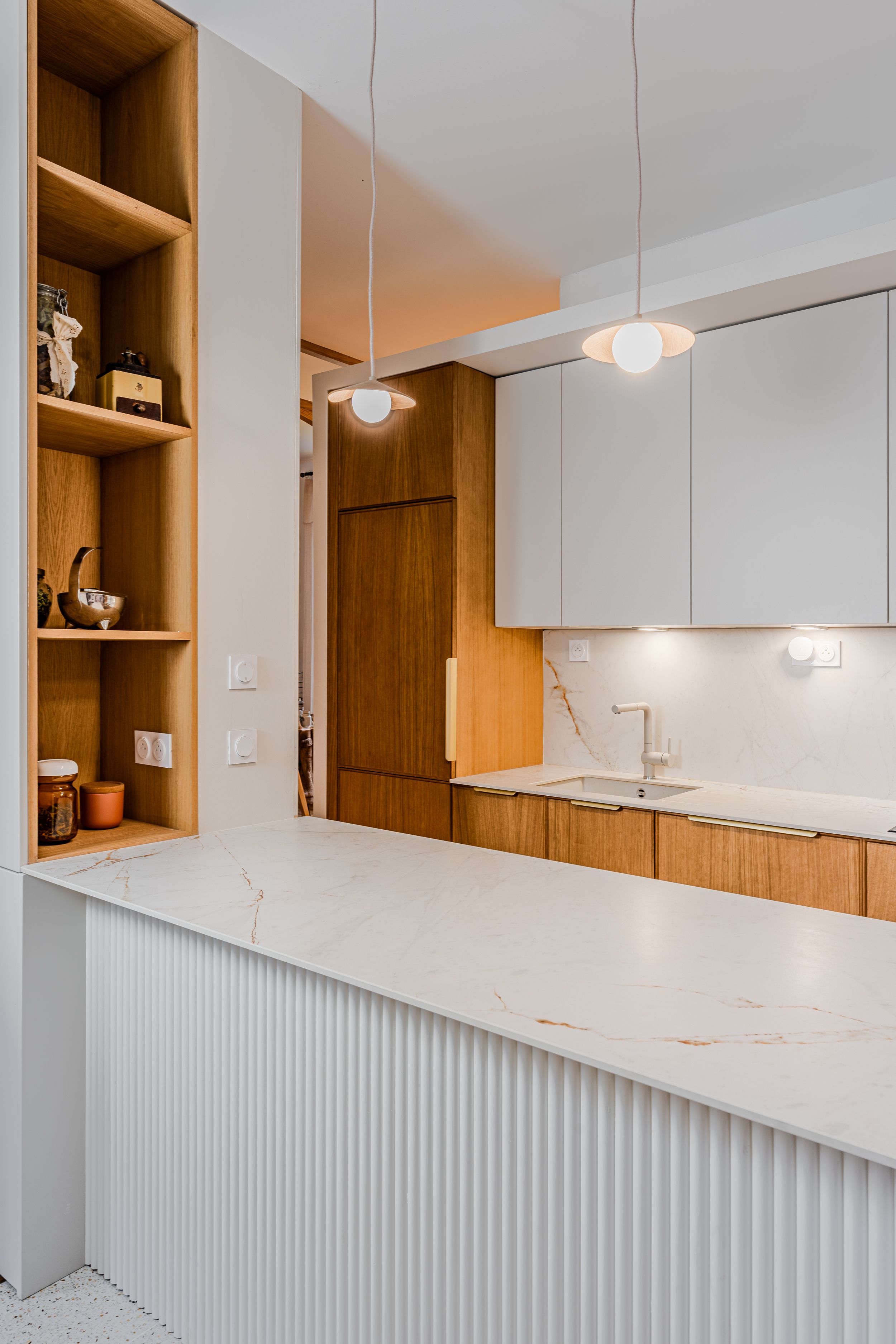 Rénovation d’une cuisine à Pessac avec rangements intégrés et claustra arrondi.