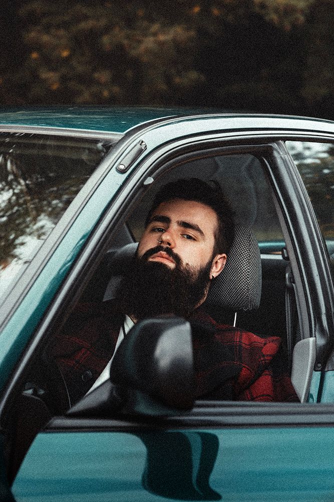 Portrait d’un homme dans une voiture, lumière naturelle et ambiance authentique pour révéler caractère et présence.