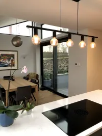 Kitchen shot, showing light fixture, sliding doors, hob and dining area.