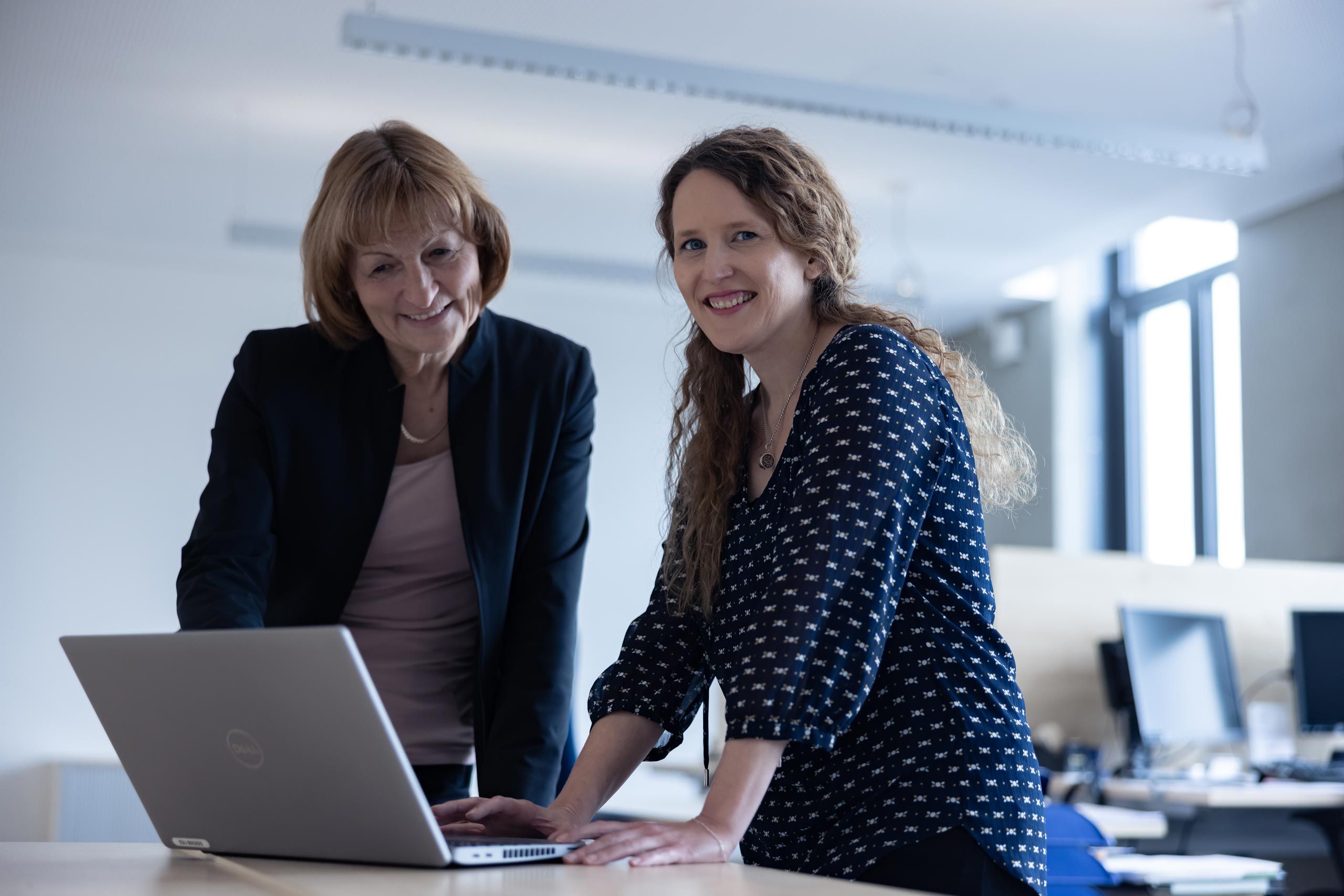 Two female employees stand at a laptop 