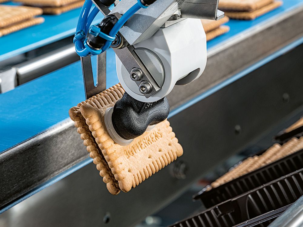 Industrieroboter sortiert Kekse auf einem Förderband in einer Produktionslinie.