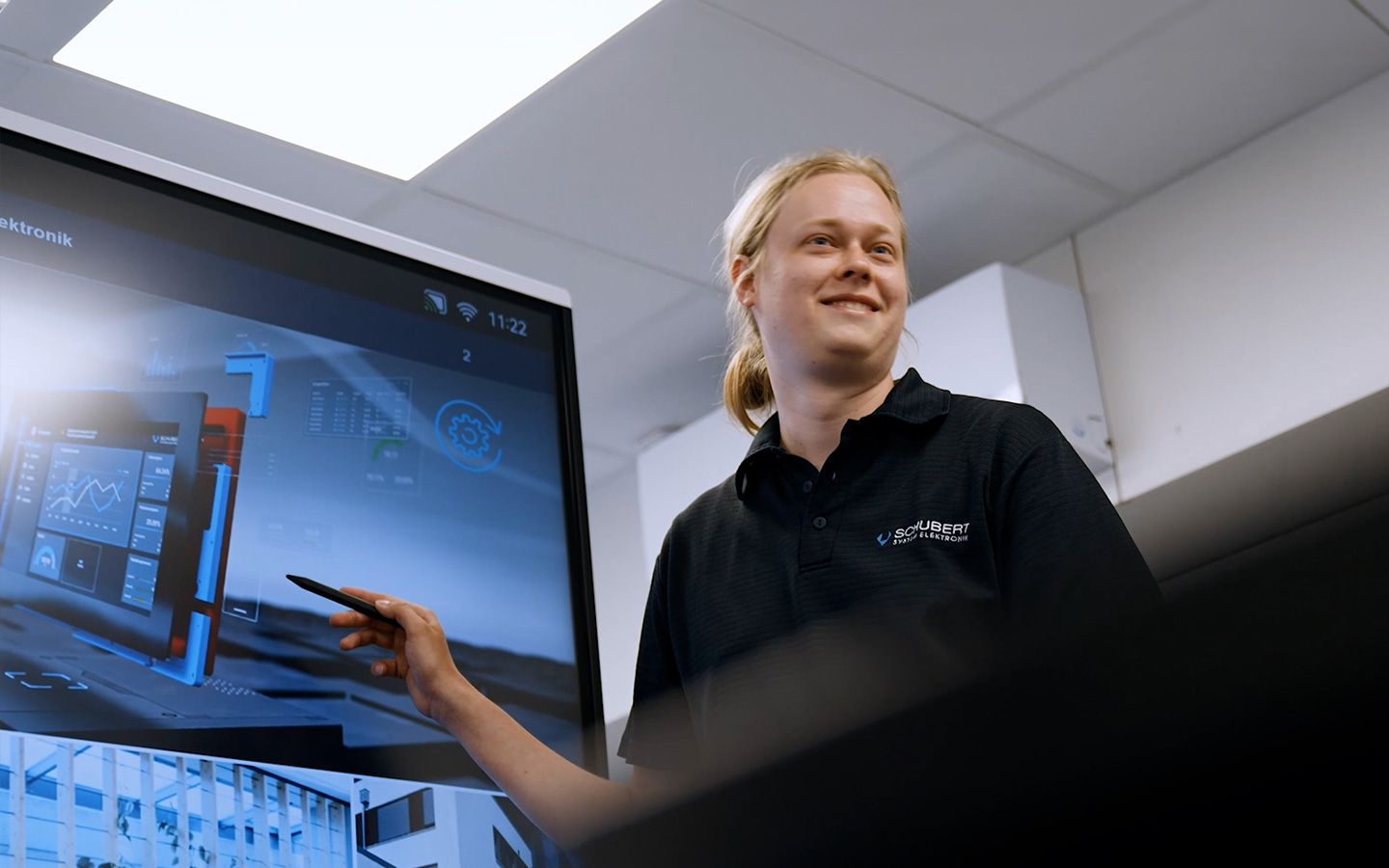 Ein Mitarbeiter ist einer Schulungssituation und steht vor einem große Bildschirm