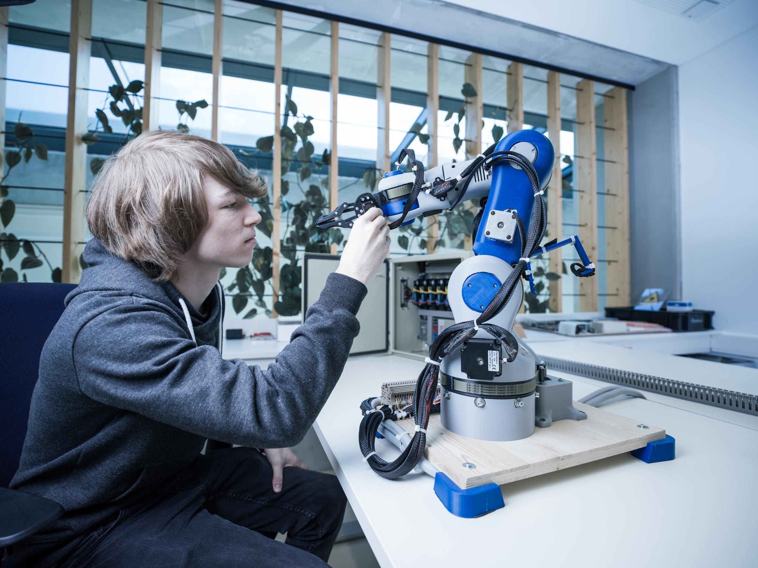 An apprentice works on a small robot 
