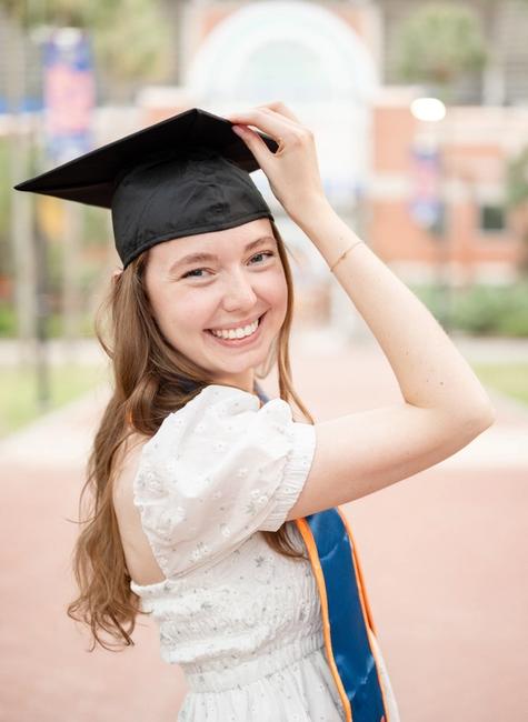 A Florida Gator Grad holding her cap for grad photos at Gator Walk