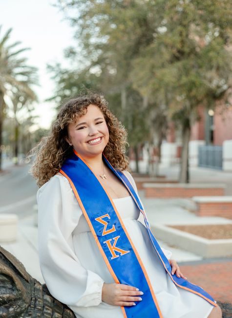 A Florida Gator Grad holding her cap for grad photos at Gator Walk