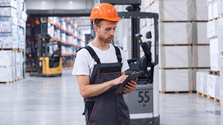 Een vorkheftruckchauffeur in het magazijn die de documentatie controleert voordat hij aan het werk gaat
