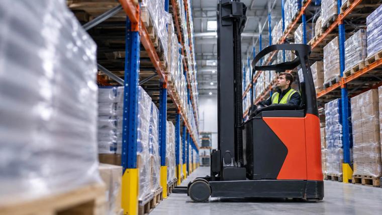 Bestuurder van een reachtruck tijdens het werk in een hoogbouwmagazijn
