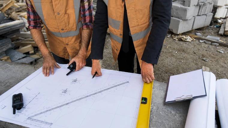 Construction workers are reviewing the technical plans on site before work begins