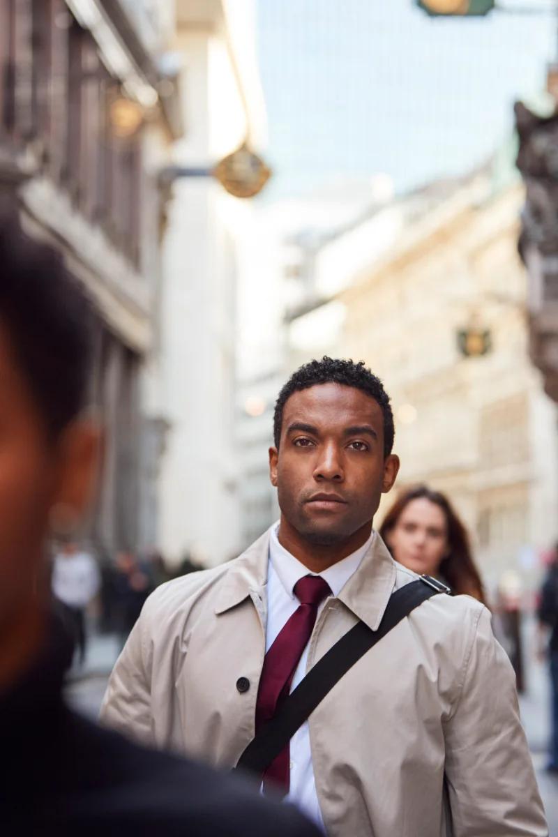 EDITORIAL — person mid-40s at a window, city or traffic behind, everyday stress
