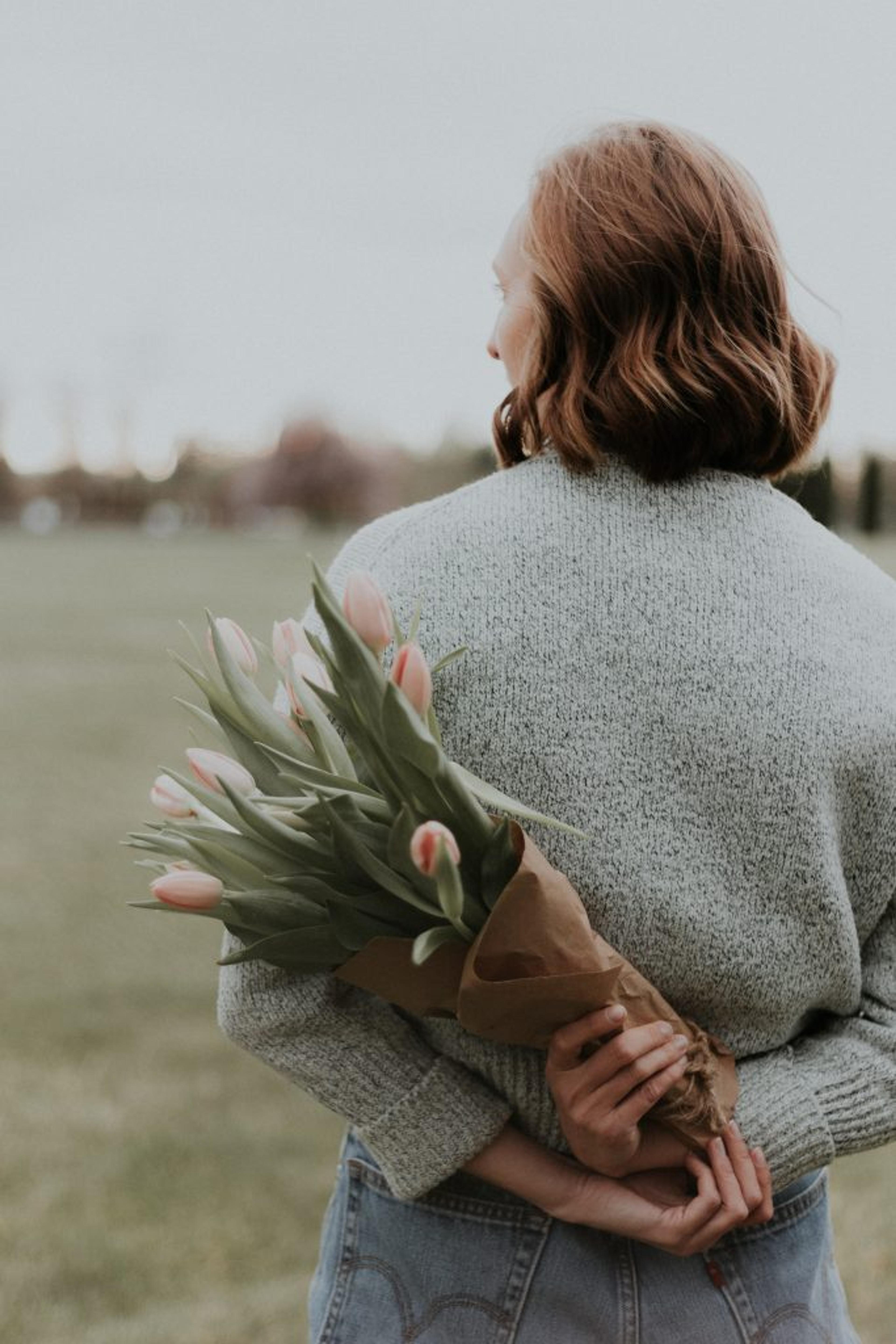 a woman is holding a bouquet of flowers behind her back .