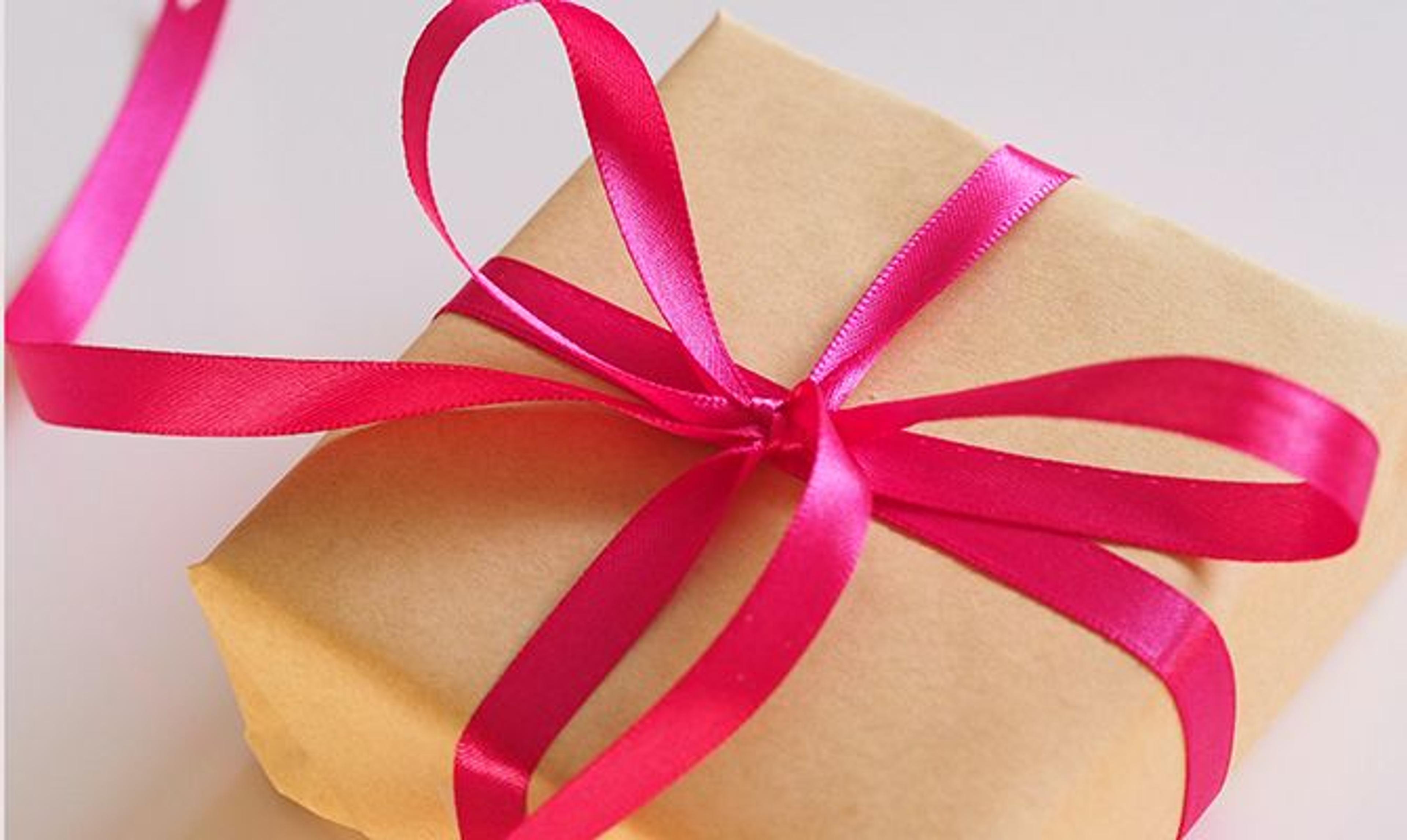 a gift wrapped in brown paper and tied with a pink ribbon .