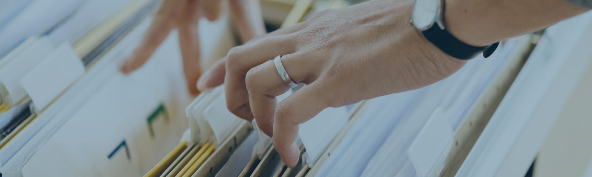 Close up stock image of business executive hands searching through paper business files. Representing blog post titled 'Transforming Business Tax reporting with technology'