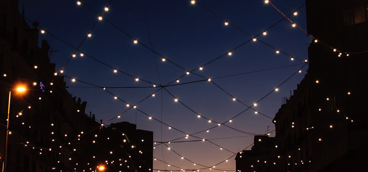 Photo of a street looking up to a night sky with fairy lights in a net formation, representing a blog titled 'Optimising network onboarding to an invoice platform'