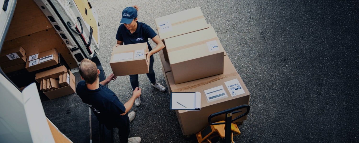 Birdseye vie of a female courier handing cardboard boxes to another colleague. Representing a blog titled: EDI for 3PL: Scale your business, maintain control