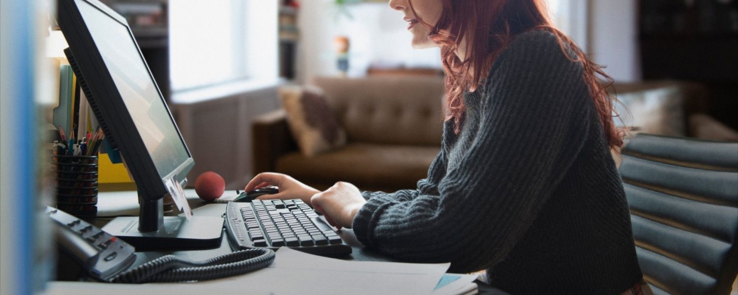 Stock image of female corporate representative sat at home-office desk, out of focus. Representing blog titled how to improve 'on-time' payments with tracked invoicing