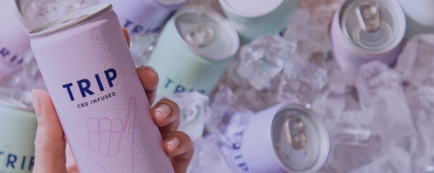 TRIP drinks EDI transformation case study header image. Close up of a hand holding a can of TRIP CBD drink above a coolbox filled with ice and more cans of TRIP drinks